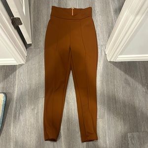 High waisted, brown cigarette pants with zipper and front pleat on each leg.